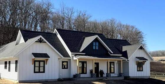 White board-and-batten modern farmhouse with black windows and cedar brackets